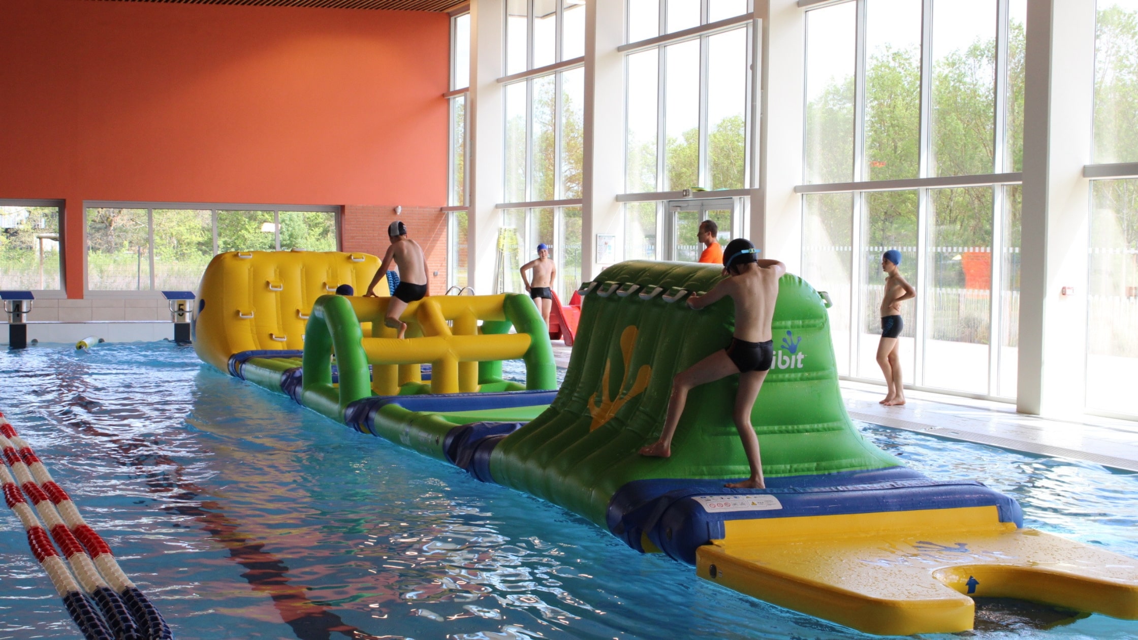 Des enfants jouant sur une installation gonflable Wibit installée dans le grand bassin du centre aquatique L'O Pastel