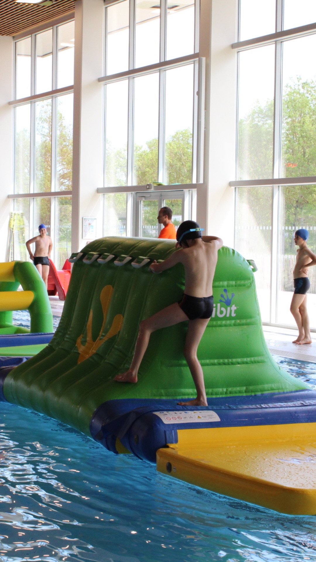 Des enfants jouant sur une installation gonflable Wibit installée dans le grand bassin du centre aquatique L'O Pastel